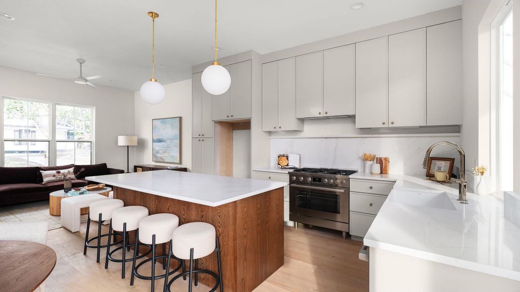 Kitchen featuring a breakfast bar, open floor plan, high end stove, a center island, and hanging light fixtures