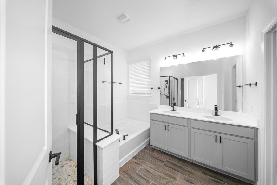 Full bathroom featuring a shower stall, a garden tub, wood finish floors, and double vanity Full bathroom featuring a shower stall, a garden tub, wood finish floors, and double vanity