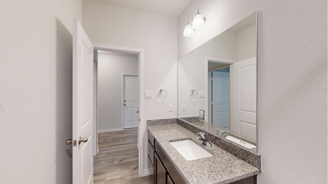 Contemporary bathroom vanity featuring a light-toned countertop, an integrated rectangular sink, a polished chrome faucet, and a large wall-mounted mirror Contemporary bathroom vanity featuring a light-toned countertop, an integrated rectangular sink, a polished chrome faucet, and a large wall-mounted mirror