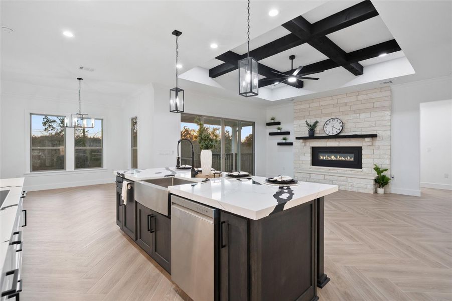 Kitchen with coffered ceiling, pendant lighting, a center island with sink, a fireplace, and dishwasher