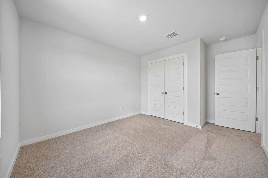 A well-lit bedroom features plush carpeting and convenient closet access. A well-lit bedroom features plush carpeting and convenient closet access.