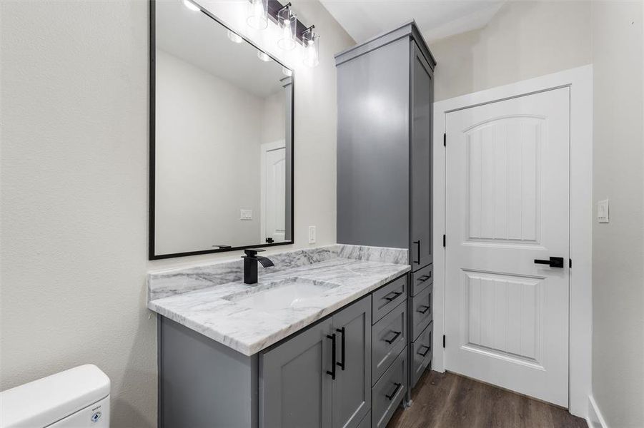 Bathroom featuring wood finished floors, vanity, and toilet