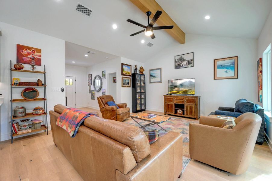 Living room featuring light wood-type flooring, a ceiling fan, recessed lighting, and lofted ceiling with beams