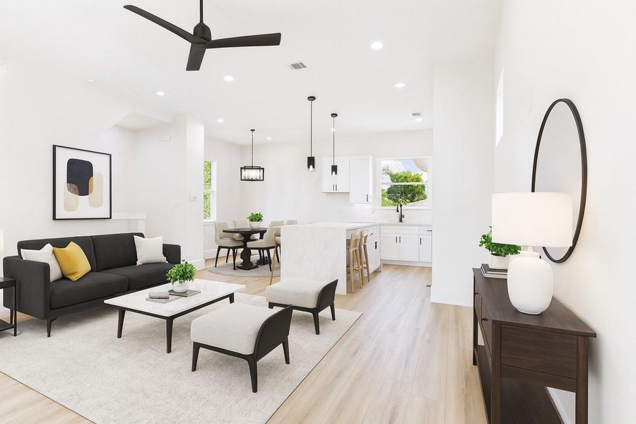 This bright, open-concept living space features modern decor.  The area seamlessly connects to a dining space and kitchen with a central island, pendant lighting, and ample natural light.  This image is AI staged.