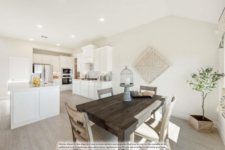 Dining area with wood table and chairs open to kitchen with white cabinets and stainless steel appliances