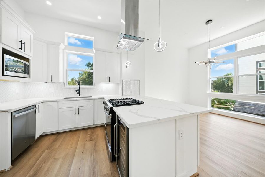 Bright and airy chef’s kitchen with modern finishes, featuring Quartz countertops, a large waterfall island with built-in wine fridge, custom soft-close cabinetry, and a stylish herringbone backsplash. Equipped with a gas cooktop, stainless steel appliances, and designer pendant lighting, this open-concept space is filled with natural light and flows seamlessly into the living and dining areas. Bright and airy chef’s kitchen with modern finishes, featuring Quartz countertops, a large waterfall island with built-in wine fridge, custom soft-close cabinetry, and a stylish herringbone backsplash. Equipped with a gas cooktop, stainless steel appliances, and designer pendant lighting, this open-concept space is filled with natural light and flows seamlessly into the living and dining areas.