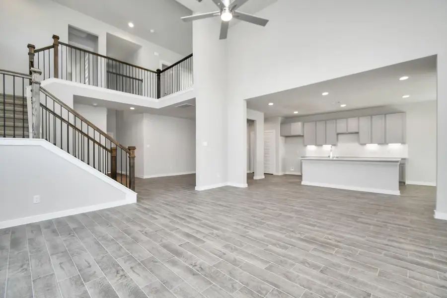 Gather the family and guests together in your lovely living room! Featuring soaring high ceilings, recessed lighting, ceiling fan, custom paint, gorgeous floors, and large windows that provide plenty of natural lighting throughout the day. Sample photo of completed home with similar floor plan. As-built interior colors and selections may vary.