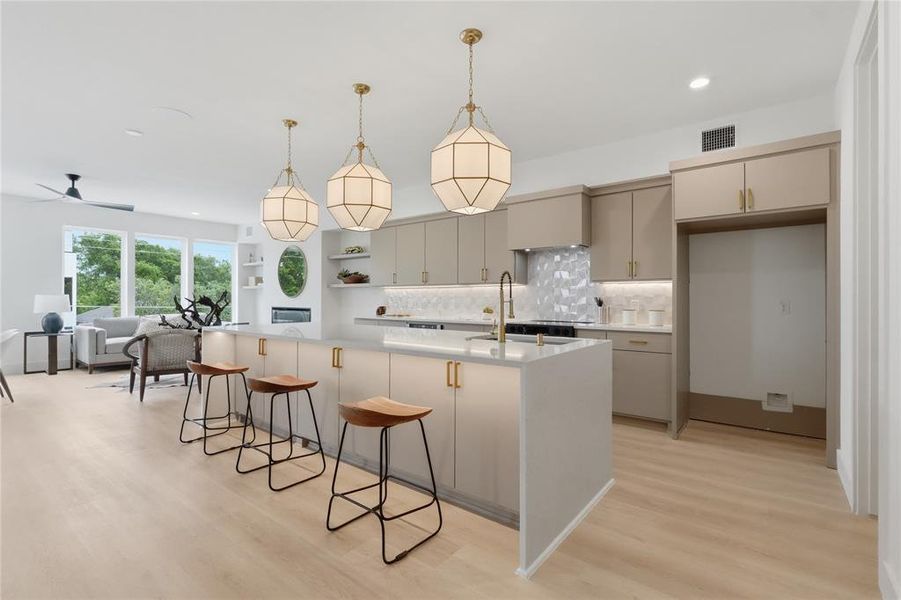 Modern kitchen island featuring a light-toned countertop, under-cabinet lighting, and three pendant light fixtures Modern kitchen island featuring a light-toned countertop, under-cabinet lighting, and three pendant light fixtures