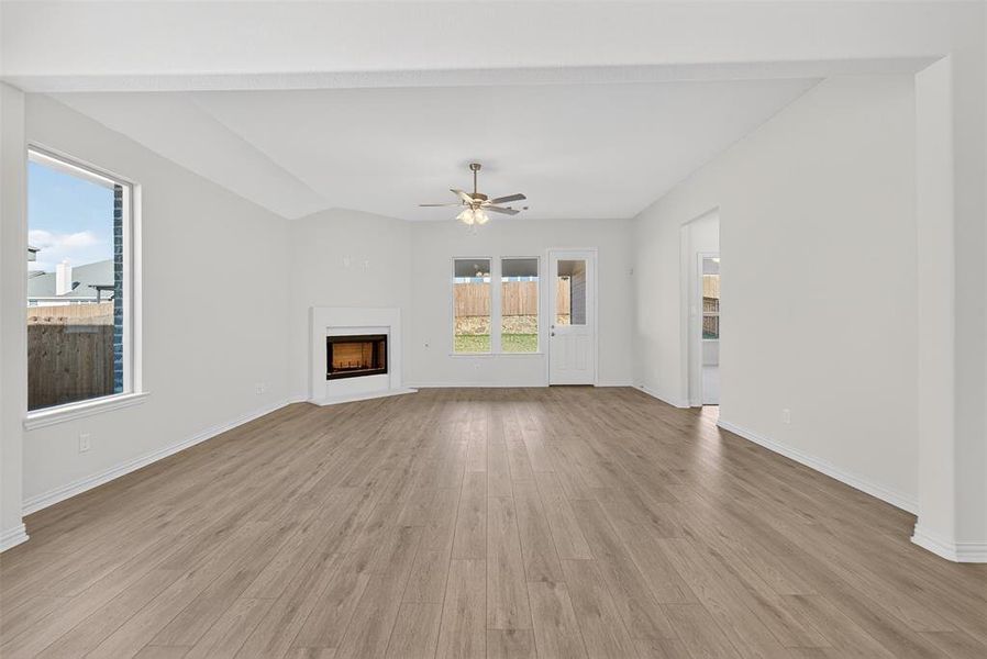 Unfurnished living room with light wood-style floors, a fireplace, and a ceiling fan