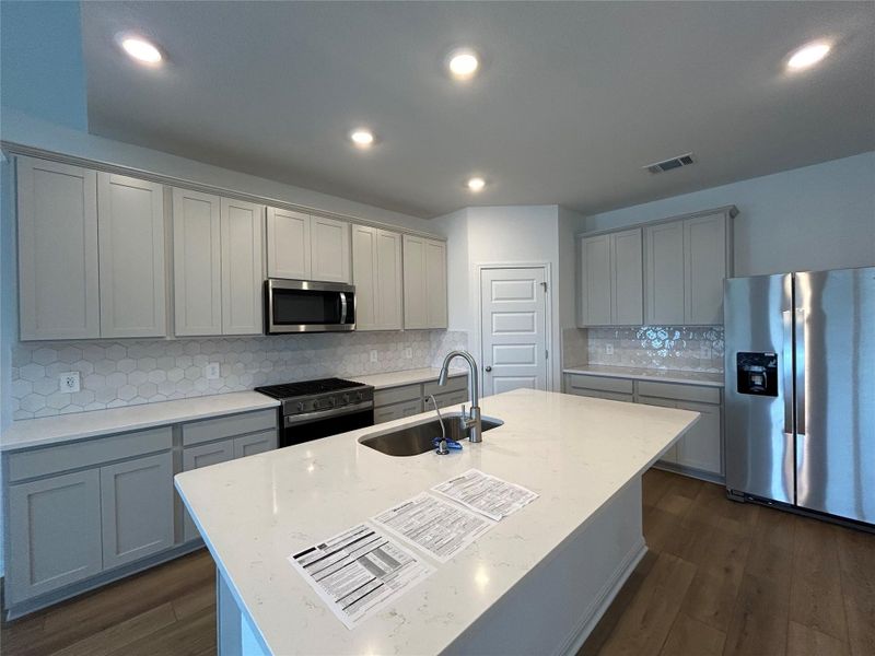 Kitchen featuring tasteful backsplash, appliances with stainless steel finishes, gray cabinetry, light stone counters, and recessed lighting Kitchen featuring tasteful backsplash, appliances with stainless steel finishes, gray cabinetry, light stone counters, and recessed lighting