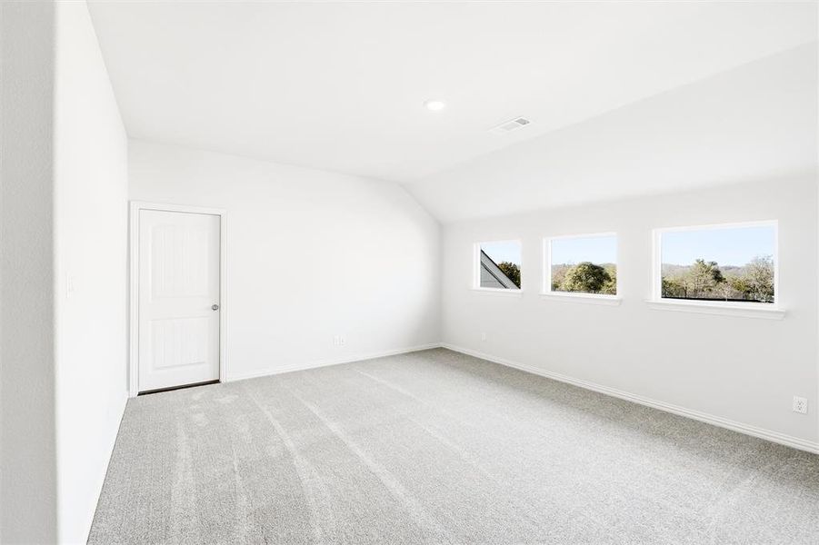 Spare room featuring light carpet and vaulted ceiling