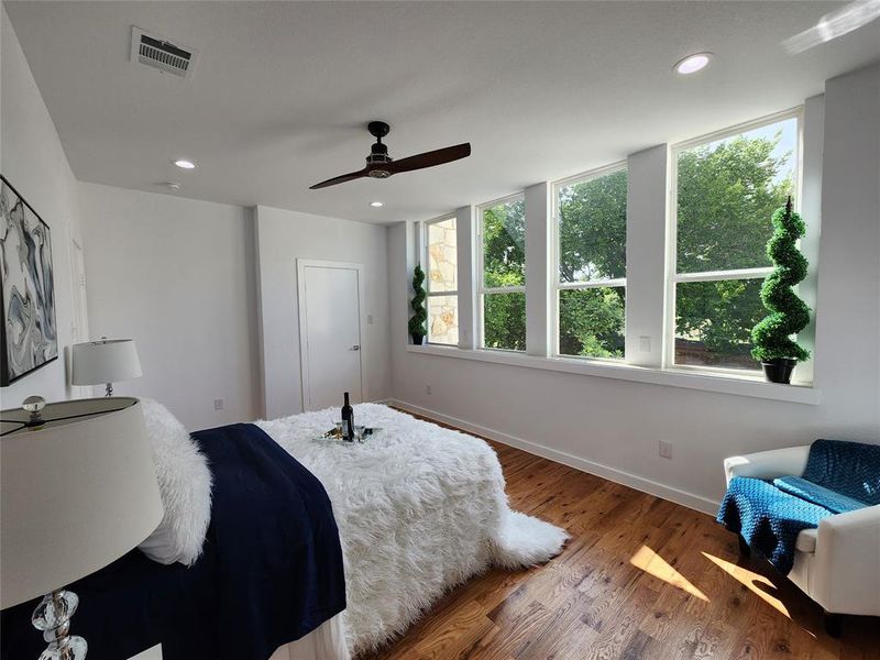 Bedroom featuring multiple windows, ceiling fan, and hardwood / wood-style floors