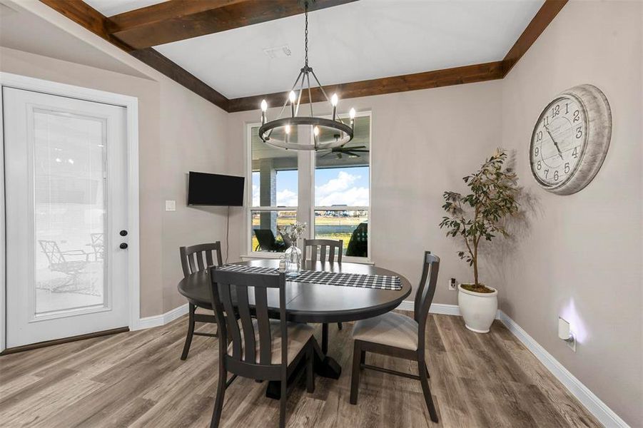 Dining area with hardwood / wood-style floors, beamed ceiling, and an inviting chandelier