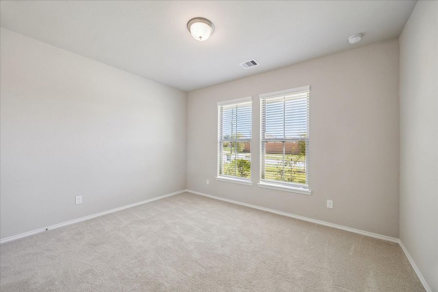 To your immediate right upon entering the home are two bedrooms and a full bathroom. This is the front bedroom with plush carpeting and plenty of closet space.