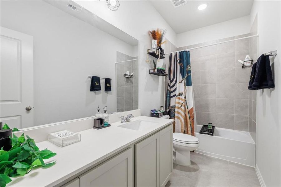 Bathroom featuring shower / bath combination with curtain, vanity, and light tile patterned floors