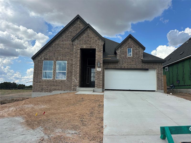 A new construction residence features a rich brick facade, a welcoming entryway, and an attached garage.
