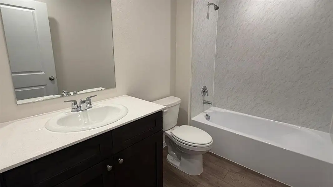 Bathroom featuring a dark wood-finish vanity with a white countertop and undermount sink, chrome faucet, and a large wall mirror Bathroom featuring a dark wood-finish vanity with a white countertop and undermount sink, chrome faucet, and a large wall mirror
