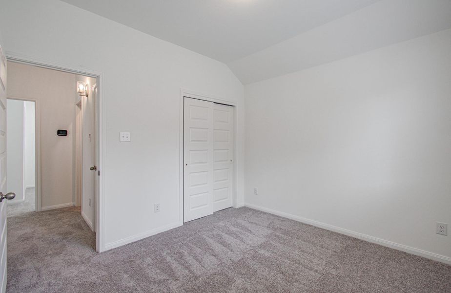 Bright and inviting bedroom featuring soft carpet flooring and a spacious closet with double doors, perfect for comfort and organization.