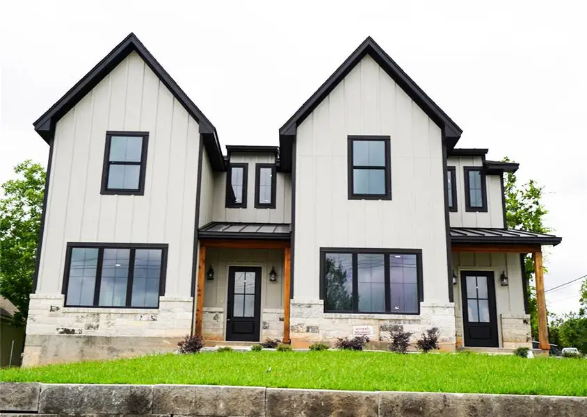 Modern farmhouse style home featuring a standing seam roof, a metal roof, and stone siding