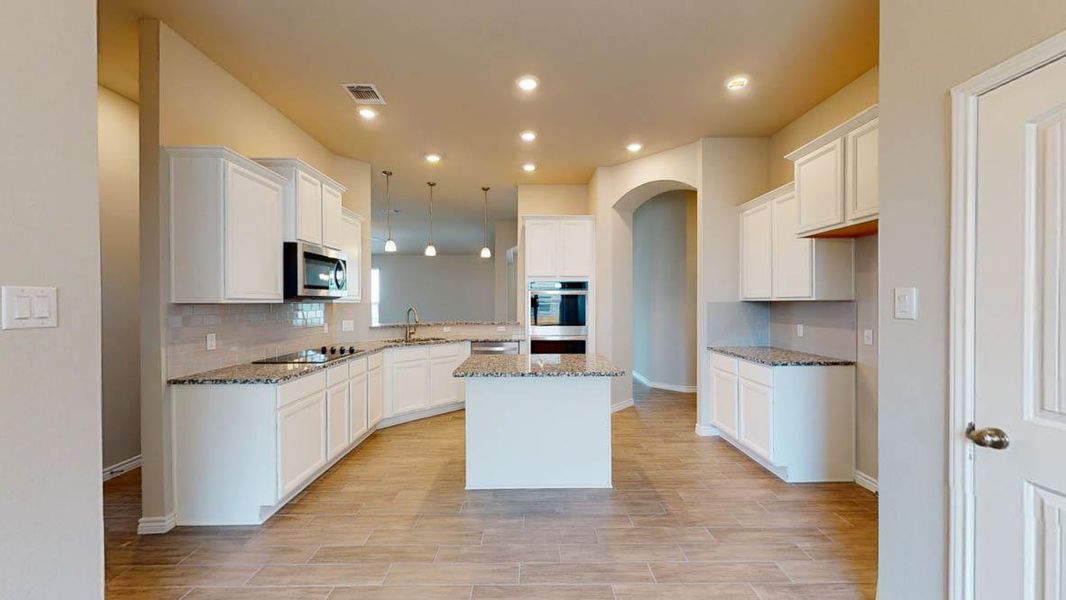 Kitchen featuring a center island, white cabinetry, light stone countertops, and wood tiled floors