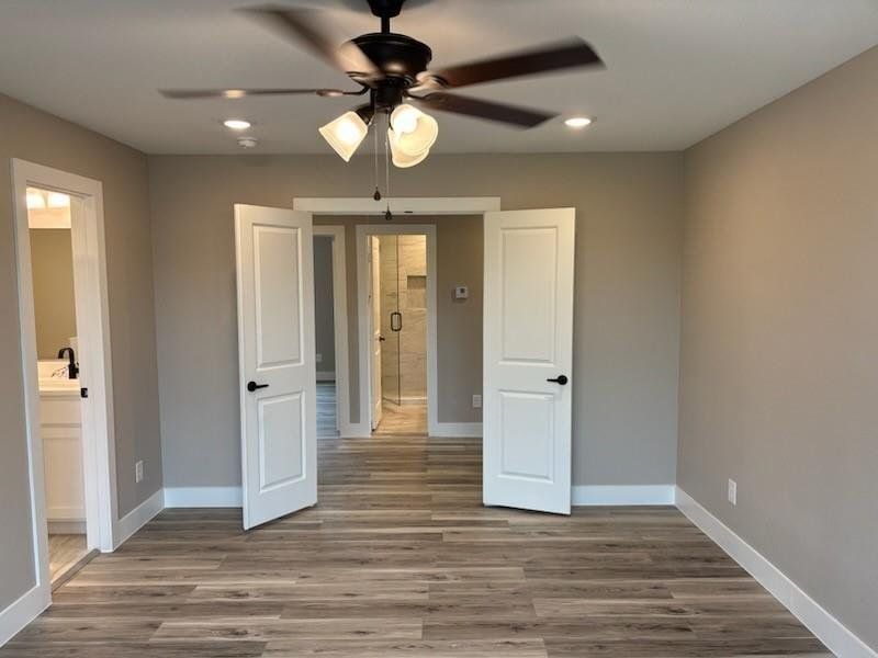 Unfurnished bedroom featuring recessed lighting, light wood-style flooring, a ceiling fan, and ensuite bath Unfurnished bedroom featuring recessed lighting, light wood-style flooring, a ceiling fan, and ensuite bath