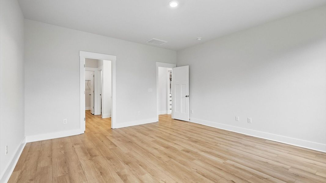 Serene and stylish primary bedroom featuring hardwood flooring and a thoughtful, modern layout at Woodglen