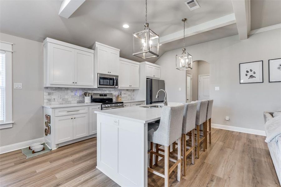 Kitchen with arched walkways, a kitchen breakfast bar, white cabinets, a kitchen island with sink, and recessed lighting Kitchen with arched walkways, a kitchen breakfast bar, white cabinets, a kitchen island with sink, and recessed lighting