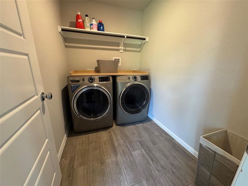 Dedicated laundry space featuring wood-finish tile flooring, a built-in shelf, and a hanging rod Dedicated laundry space featuring wood-finish tile flooring, a built-in shelf, and a hanging rod