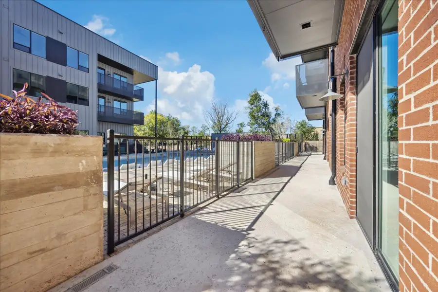 Concrete pathways lead to a community pool, nestled between modern brick and panel-sided buildings. Concrete pathways lead to a community pool, nestled between modern brick and panel-sided buildings.