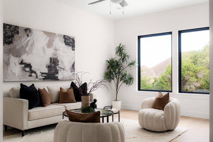 Hardwood flooring and high ceilings amplify this living space, offering a peaceful view through tall windows.