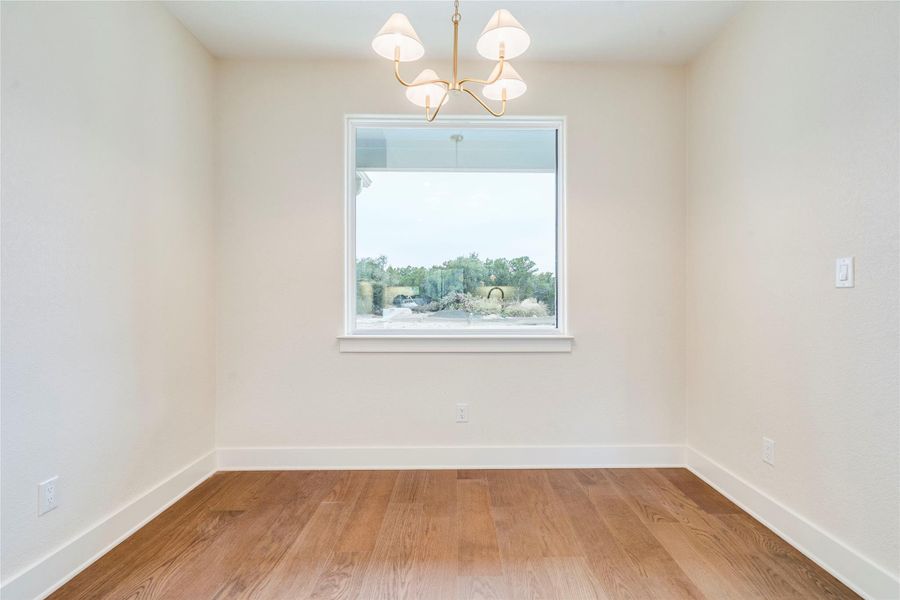 Empty room featuring light wood-type flooring and a chandelier