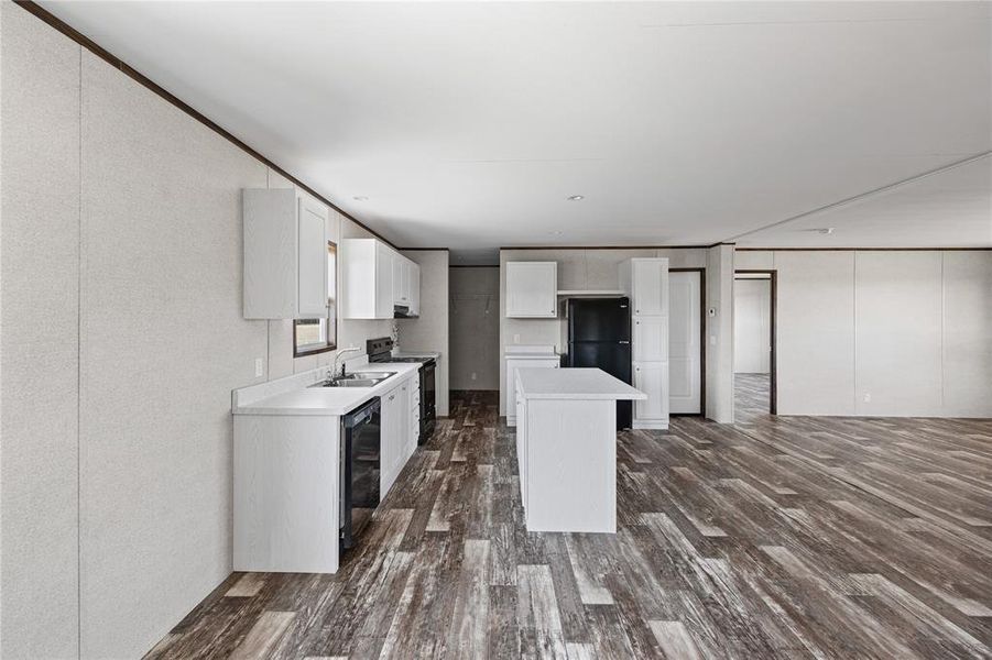 Kitchen featuring a center island, sink, dark wood-type flooring, black appliances, and white cabinets