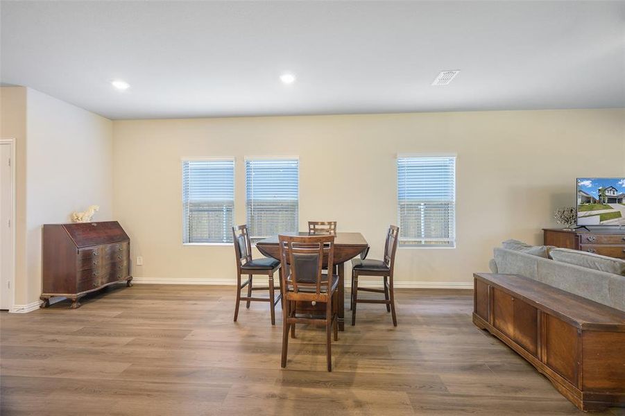 Spacious living area featuring wood-finish flooring, recessed lighting, and light-toned walls Spacious living area featuring wood-finish flooring, recessed lighting, and light-toned walls