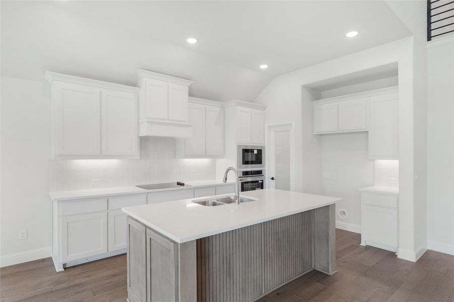 White kitchen with center island, sink, stainless steel wall ovens, and dark hardwood floors