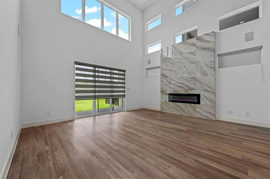 Unfurnished living room with a fireplace, plenty of natural light, a high ceiling, and wood-type flooring