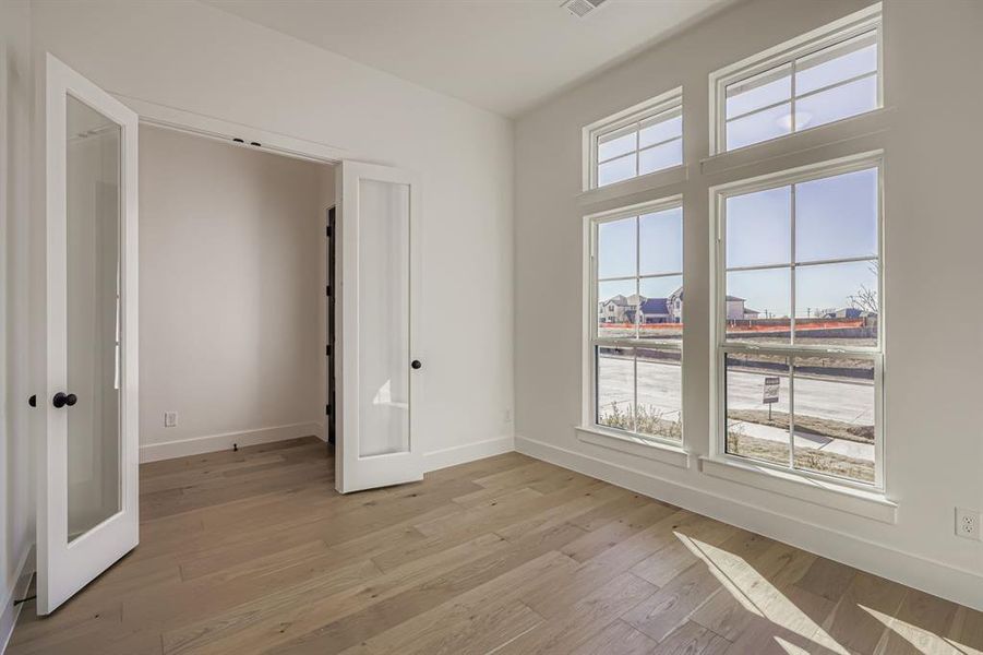Unfurnished bedroom featuring light wood-type flooring and french doors