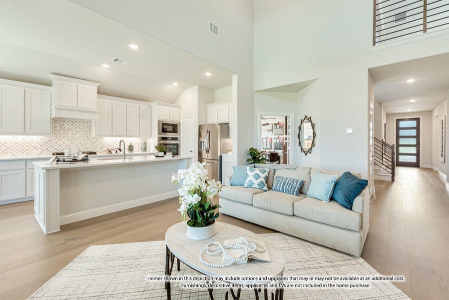 Open-concept living room and kitchen with high ceilings, white cabinets, large island, and hardwood floors Open-concept living room and kitchen with high ceilings, white cabinets, large island, and hardwood floors