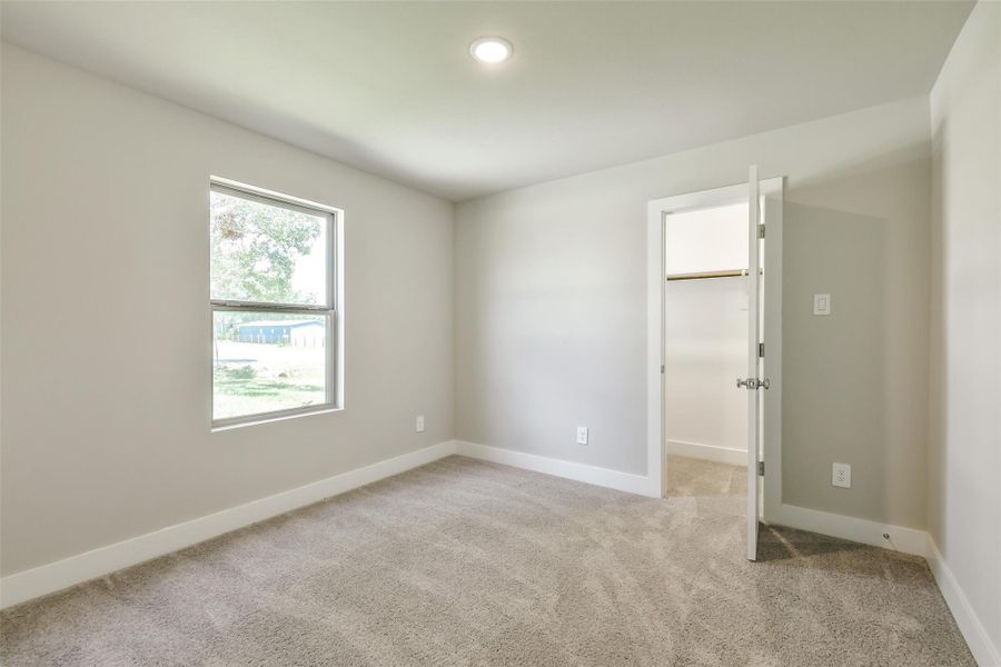One of two secondary bedrooms, featuring plush carpet, a walk-in closet and a window overlooking the front yard.