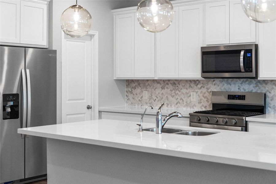 The kitchen backsplash is Minute Mosaix in Daphne White - Herringbone. So gorgeous and compliments the pure white quartz and cabinets.
