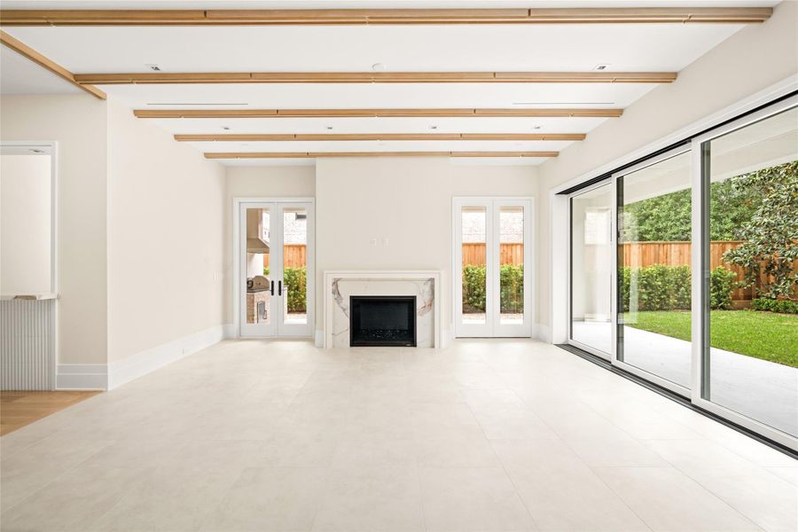 A statement fireplace anchors the space, while modern white oak beam detailing and expansive glass doors create a seamless connection to the outdoors.