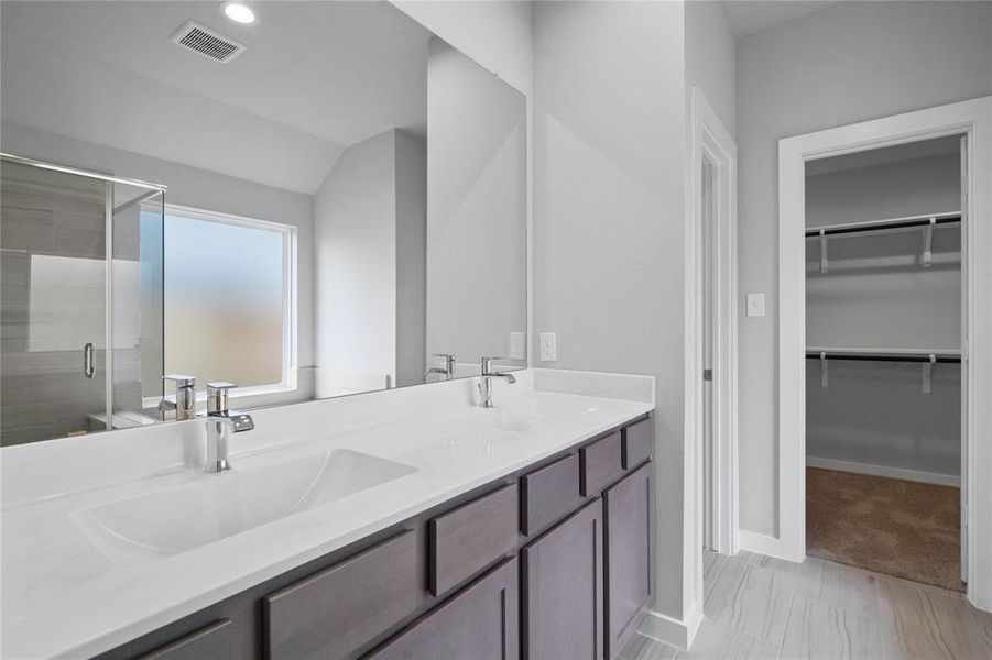 This primary bathroom is definitely move-in ready! Featuring stained cabinets with light countertops, spacious walk-in closet with shelving, high ceilings, custom paint, sleek and dark modern finishes.