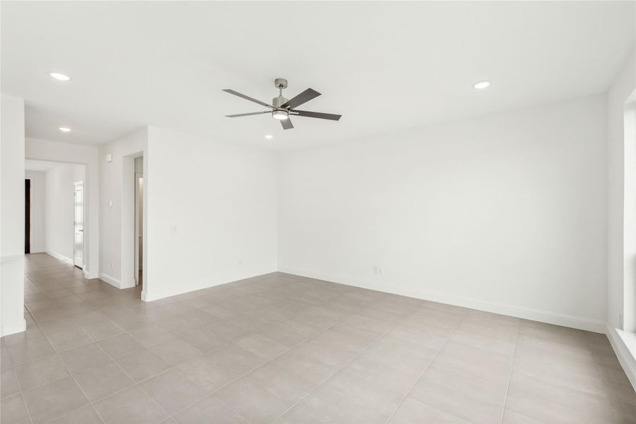 Empty living room with gray tile floors, ceiling fan, and recessed lighting Empty living room with gray tile floors, ceiling fan, and recessed lighting