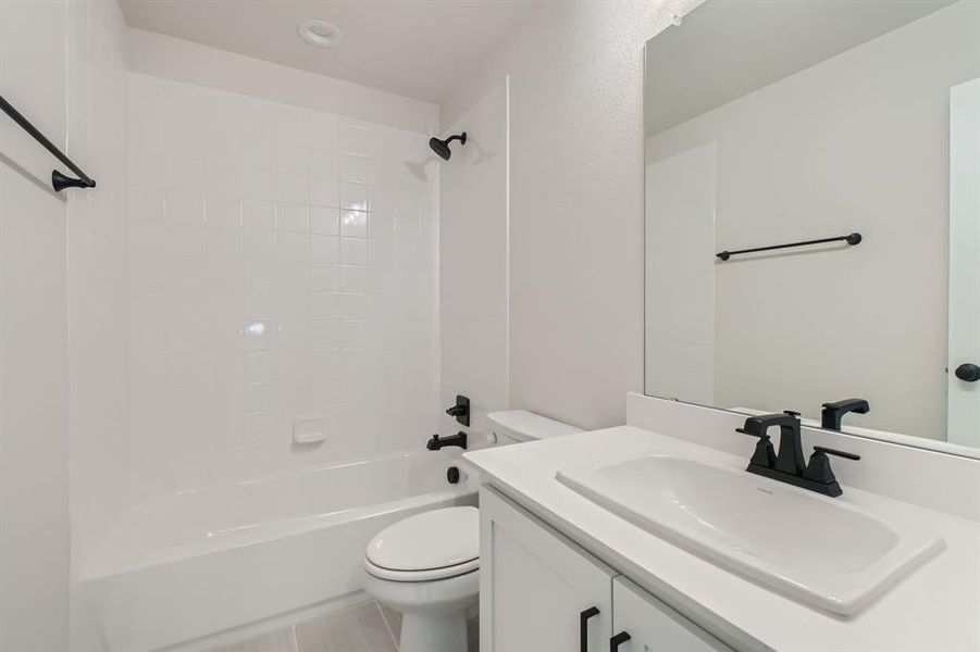 Full bathroom with vanity, toilet, tile patterned floors, and shower / bathing tub combination