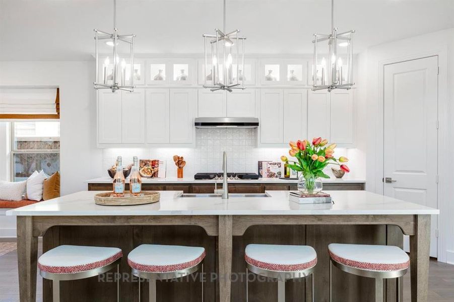 Kitchen featuring glass insert cabinets, white cabinetry, decorative backsplash, dark wood-type flooring, and a breakfast bar