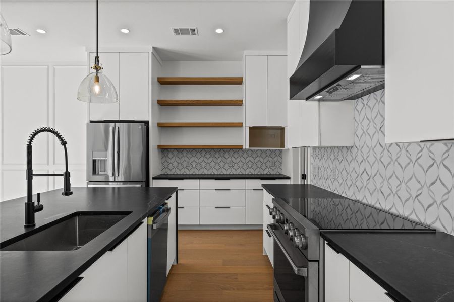 Kitchen with stainless steel appliances, white cabinets, hanging light fixtures, open shelves, and dark wood-type flooring Kitchen with stainless steel appliances, white cabinets, hanging light fixtures, open shelves, and dark wood-type flooring