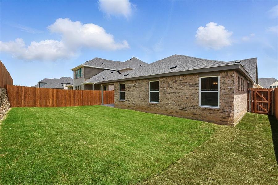 Back of property featuring a shingled roof, brick siding, and a fenced backyard Back of property featuring a shingled roof, brick siding, and a fenced backyard