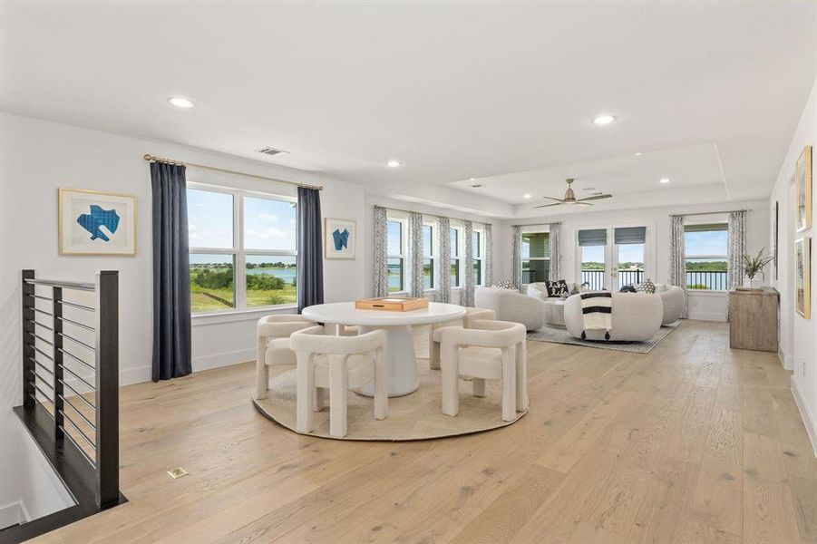 Dining room featuring a tray ceiling, light wood-style flooring, recessed lighting, a water view, and ceiling fan Dining room featuring a tray ceiling, light wood-style flooring, recessed lighting, a water view, and ceiling fan