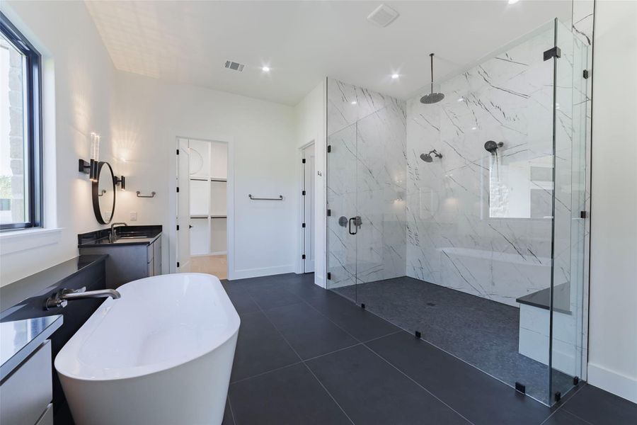Owner's bathroom featuring a spa like walk-in shower, a freestanding soaking tub, a spacious closet, dual vanities, and recessed lighting Owner's bathroom featuring a spa like walk-in shower, a freestanding soaking tub, a spacious closet, dual vanities, and recessed lighting