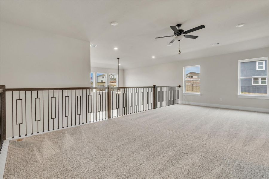 A spacious upper-level loft area offers versatility and overlooks the downstairs living spaces.