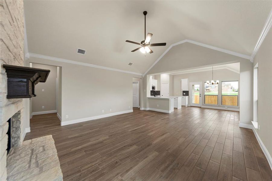 Spacious open-concept interior featuring wood-finish tile flooring and vaulted ceilings